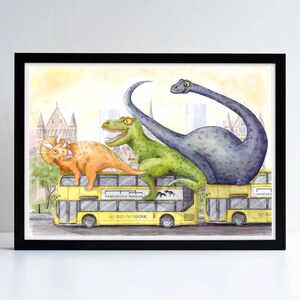 Op de afbeelding: Een ingelijste aquarelillustratie met een gele dubbeldekkerbus met het opschrift Bee Network en Manchester Museum. Een oranje triceratops, een groene tyrannosaurus en een grote paarse langnekdinosaurus zitten boven op de bus.