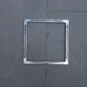 May include: A silver metal square frame with a smooth, polished finish. The frame is set against a gray tiled background.