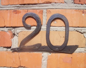 May include: A metal house number sign with the number "20" attached to a brick wall.