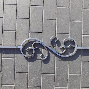 May include: A silver metal decorative scroll with a simple, elegant design. The scroll is made of a single piece of metal and has a smooth, polished finish.