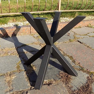 Op de afbeelding: Zwarte metalen tafelpoot met een stervormig ontwerp. De poot heeft vijf punten en is gemaakt van dik metaal.