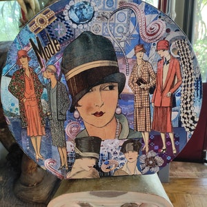 1927 年の帽子をかぶった女性をファッション紙でコラージュしてカスタマイズした大きな古い帽子箱。保管と装飾用に「HATS ON BLUE」と名付けられています。