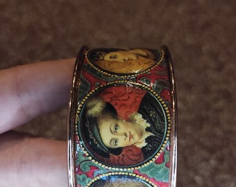 Coppery brass cuff bracelet paper collage portraits in medallion royal characters renaissance style on red background "REIGN"