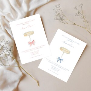 K&ouml;nnte beinhalten: Zwei wei&szlig;e Einladungskarten mit einer Aquarell-Illustration eines Kuchengestells mit einer rosa und blauen Schleife. Der Text auf den Karten lautet "Schlie&szlig;en Sie sich uns zu einer Bridal Shower zu Ehren von Margaret Dapurt an".