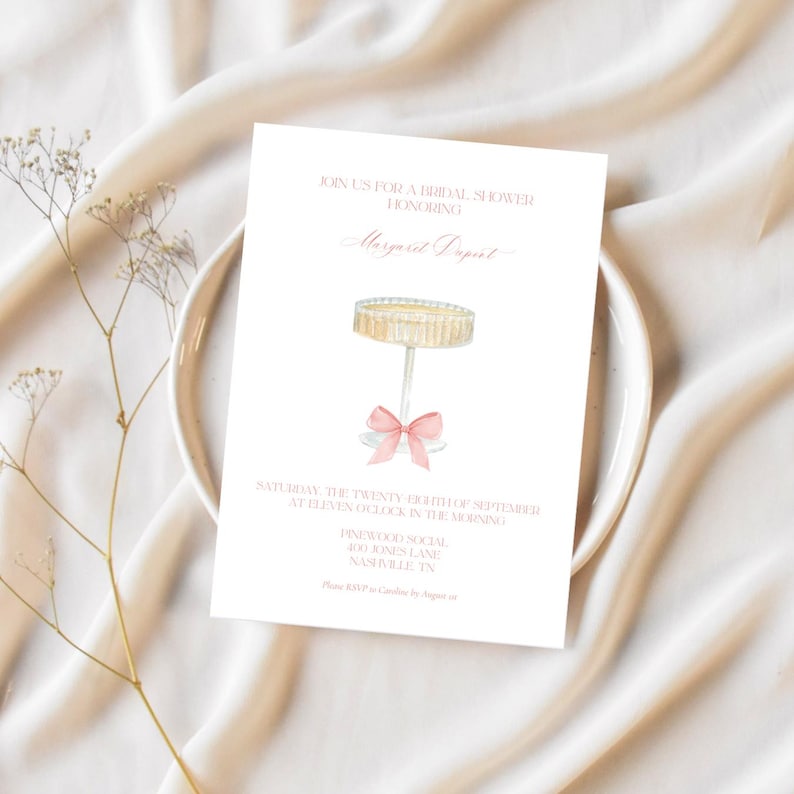 K&ouml;nnte beinhalten: Eine wei&szlig;e Einladung zu einer Brautparty mit rosa Schrift. Die Einladung zeigt eine Aquarell-Illustration eines Kuchentellers mit einer rosa Schleife. Der Text lautet: "Schlie&szlig;en Sie sich uns zu einer Brautparty zu Ehren von Margaret Dupint an. Samstag, der 24. September um 11 Uhr morgens. Pinewood Social 400 Jones Lane Nashville, TN"
