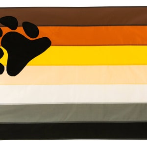 May include: A pride flag with seven horizontal stripes in brown, orange, yellow, beige, white, gray, and black. A black bear paw print is centered on the top three stripes.
