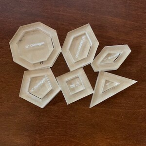 May include: A set of six clear plastic geometric shapes, each with a different shape and size. The shapes include a 1/2 inch octagon, a 1/2 inch hexagon, a 1/2 inch diamond, a 1/2 inch pentagon, a 1/2 inch square, and a 1/2 inch triangle.