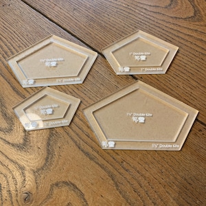 May include: Four clear plastic quilting templates in the shape of a double kite. The templates are labelled with the sizes 1", 1 1/4", 1 1/2", and 1 3/4".