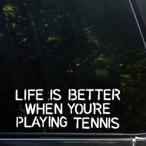 May include: A black car window with a white vinyl decal that reads "Life is better when you're playing tennis."