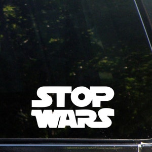 May include: White vinyl decal with the text "STOP WARS" in a bold, blocky font. The decal is designed to be applied to a car window or other smooth surface.