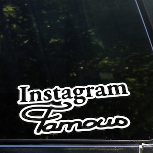 Può includere: Un adesivo in vinile bianco con il testo "Instagram Famous" in un font bianco e nero. L'adesivo è su un finestrino di un'auto nera.
