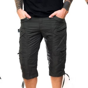 Puede incluir: Un pantalón corto de carga gris oscuro con cierres ajustables de cordón en la parte inferior. El pantalón corto tiene múltiples bolsillos y un ojal para cinturón.