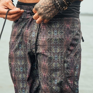 May include: Black swimming trunks with a colourful geometric pattern. The drawstring is black and the waistband is black with a black elastic band.