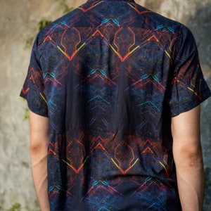 May include: A black short-sleeved button-down shirt with a geometric pattern in shades of red, orange, yellow, and blue.