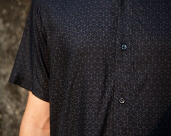 May include: A black short-sleeved button-down shirt with a geometric pattern. The shirt has a collar and a button closure.