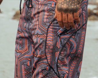 May include: Board shorts featuring a black, orange, and light blue geometric circuit-board pattern. The shorts have a black waistband with a drawstring closure and a side pocket with a black zipper. The fabric displays a repeating angular design.