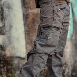 May include: Grey cargo trousers with a geometric pattern and multiple zipped pockets.