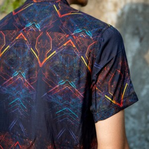 May include: A black short-sleeved shirt with a colorful geometric pattern. The pattern features lines and shapes in shades of red, orange, yellow, blue, and green.