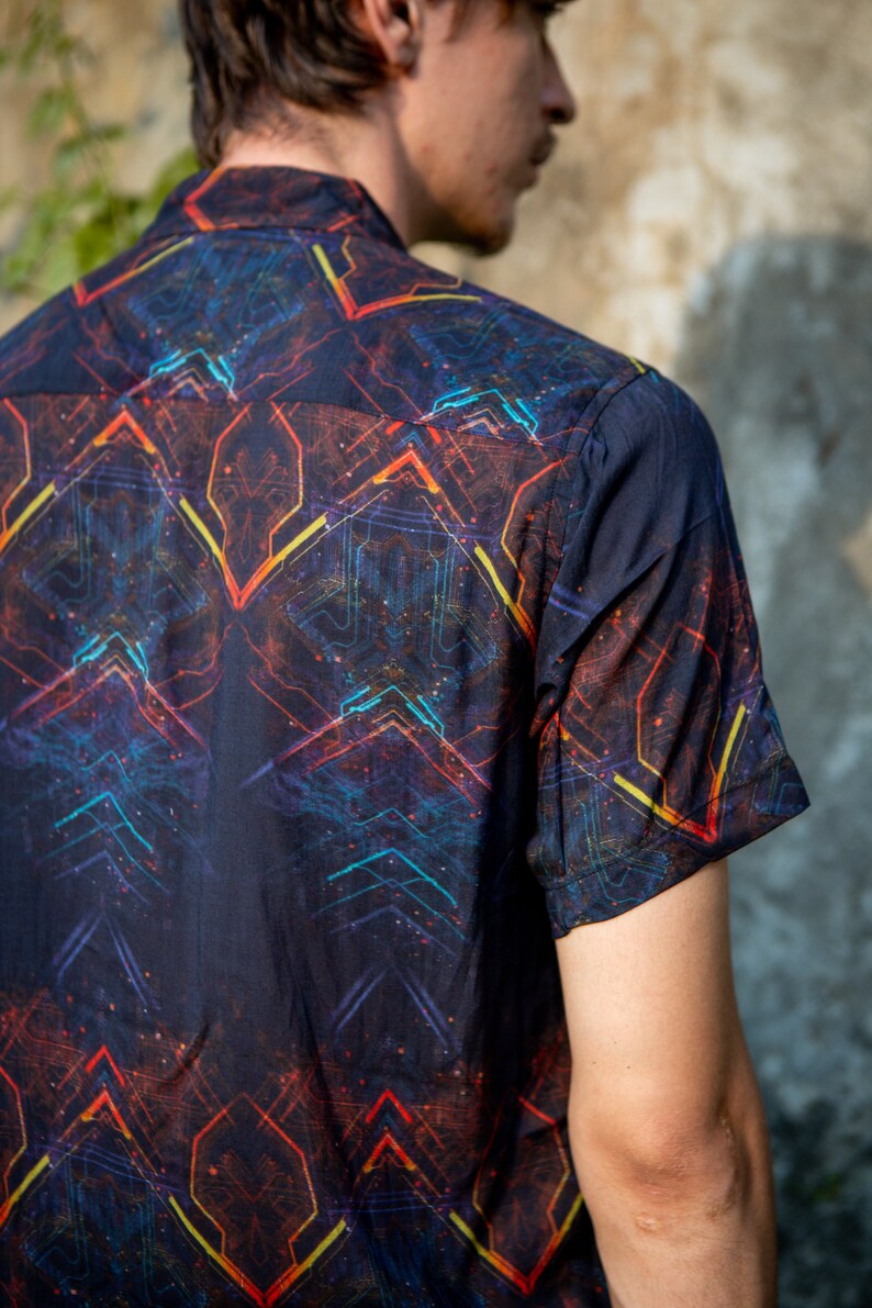 May include: A black short-sleeved shirt with a colorful geometric pattern. The pattern features lines and shapes in shades of red, orange, yellow, blue, and green.