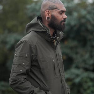 Men’s olive green GORE-TEX soft shell winter jacket with hood – side view outdoors.