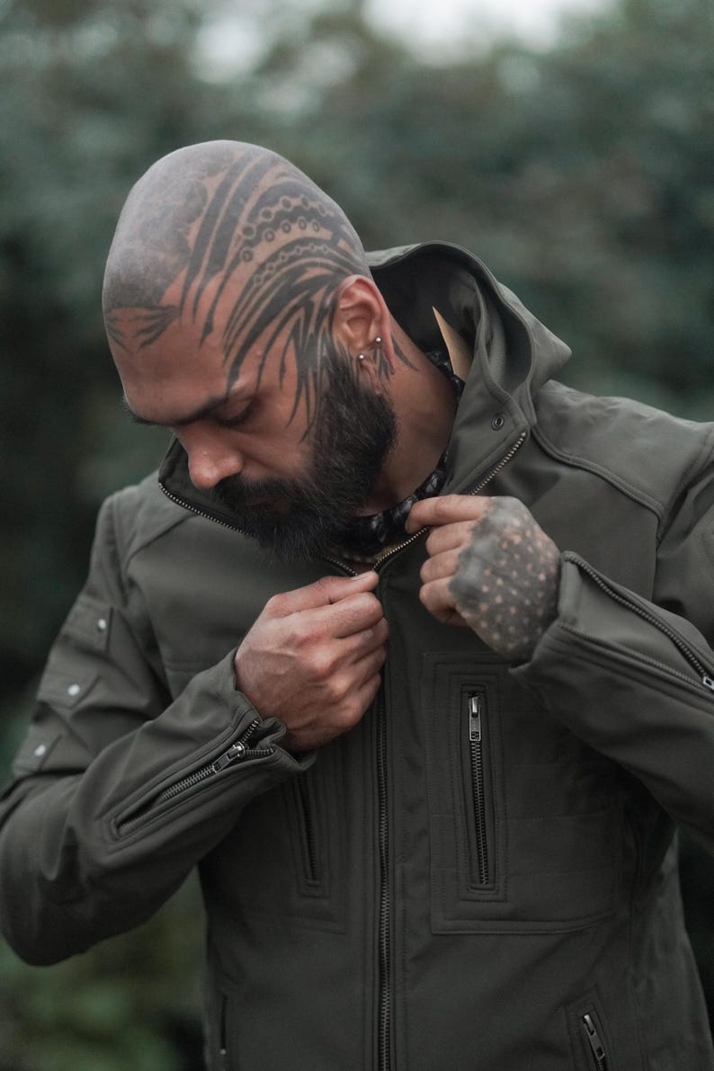 Man wearing windproof olive green soft shell winter jacket zipping up front closure.