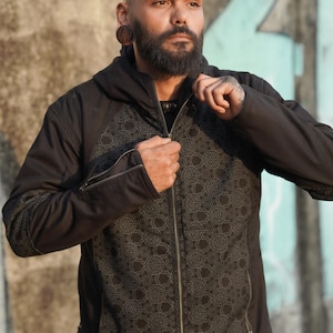 Puede incluir: Una chaqueta negra con capucha y un patrón geométrico en la parte delantera. La chaqueta tiene una cremallera y una capucha.