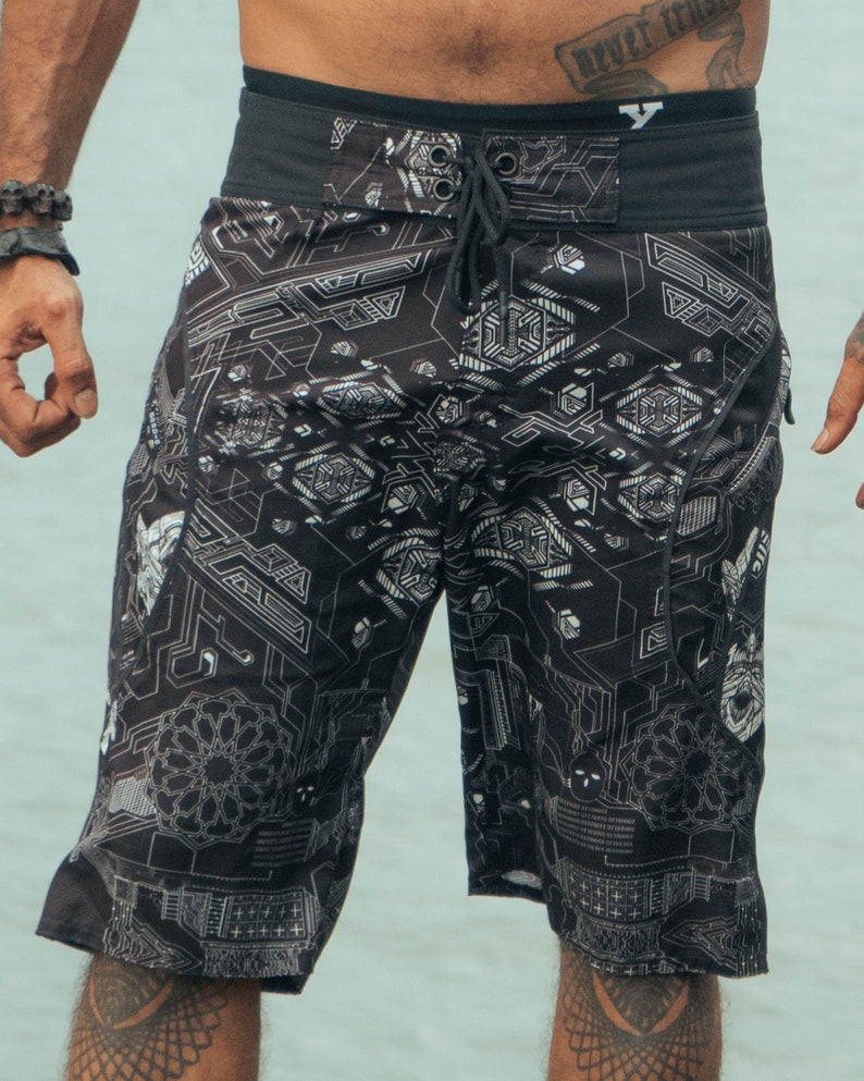 Black swimming trunks with a white geometric pattern. The waistband is black with a drawstring.