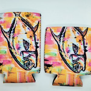 May include: Two colorful neoprene can coolers with a black and white illustration of a fish on a pink, yellow, and green background.