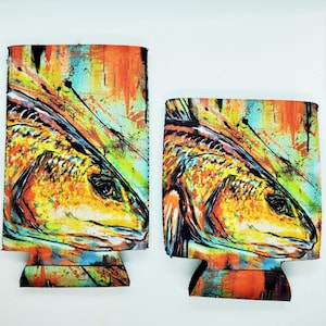 May include: Two colorful neoprene can coolers with a redfish design. The coolers feature a vibrant abstract background with splashes of orange, yellow, blue, and green. The redfish is depicted in a realistic style with detailed scales and fins.