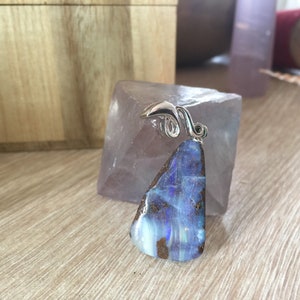 May include: A blue opal pendant with a silver bail. The opal is a teardrop shape and has a shimmery, iridescent finish.