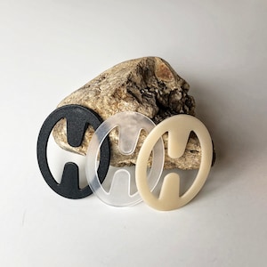 May include: Three bra strap adjusters, one black, one clear, and one off-white. The adjusters are shaped like a figure eight.