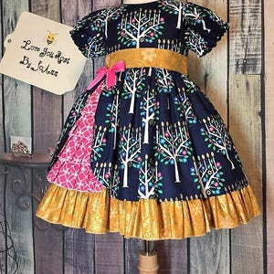 Peut inclure: Robe bleu marine avec un motif d'arbres blancs, une ceinture dor&eacute;e et un n&oelig;ud rose. La robe a un ourlet &agrave; volants et un panneau &agrave; motifs roses. L'&eacute;tiquette indique "Love You Most By SoAnn".