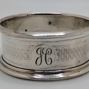 May include: A white ceramic mug with a black handle and the text "But First, Coffee" in a black, handwritten-style font. The mug is on a white surface.