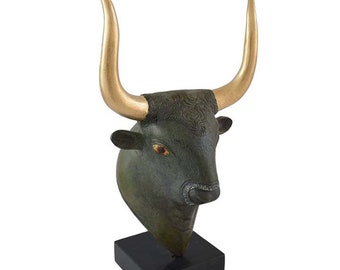 Pode incluir: Uma escultura de cabeça de touro verde escuro com chifres dourados sobre uma base preta. Os olhos do touro são vermelhos e a escultura é detalhada com pelo texturizado.