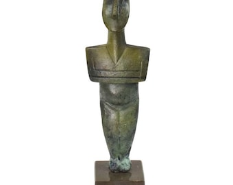 May include: A bronze statue of a standing figure with a simplified, geometric design. The figure has a rounded head, a wide torso, and stylized limbs. The statue is mounted on a square base.