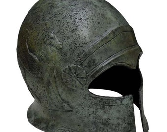 Pode incluir: Um capacete grego de bronze com um design alado e um motivo floral. O capacete tem uma crista pontiaguda e uma máscara facial.