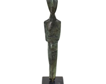 May include: A bronze sculpture of a standing figure with arms crossed. The sculpture is on a black marble base.