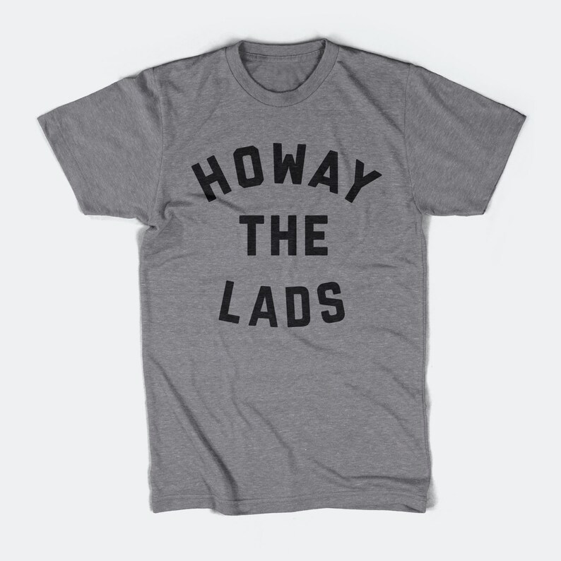 May include: A heather grey t-shirt with the text "HOWAY THE LADS" printed in black.