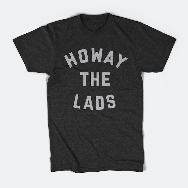 May include: A dark grey t-shirt with the text "Howay the Lads" printed in white.