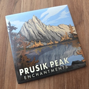 May include: Square tile featuring a landscape illustration of Prusik Peak with a lake and trees. The artwork has a mountain range in the background, with the text "PRUSIK PEAK ENCHANTMENTS" in white.