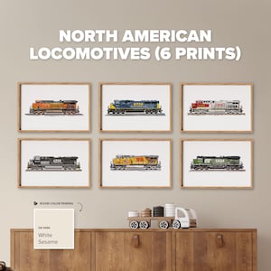 May include: Six framed art prints titled NORTH AMERICAN LOCOMOTIVES (6 PRINTS) featuring detailed illustrations of various diesel trains in orange, blue, red, black, yellow, and green color schemes, displayed in a grid on a light beige wall.
