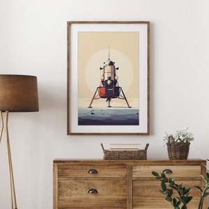 Pu&ograve; includere: Una stampa artistica incorniciata con un'illustrazione stilizzata del Modulo Lunare Apollo su una superficie lunare. L'opera d'arte ha un'estetica retr&ograve; con una tavolozza di colori tenui di arancione, beige e grigio. La stampa &egrave; esposta su una parete bianca sopra una cassettiera in legno.