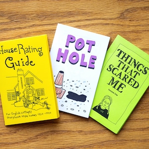 Puede incluir: Tres peque&ntilde;os libros de bolsillo coloridos con ilustraciones dibujadas a mano. El primer libro es amarillo con texto negro y un dibujo de una casa. El texto dice "House Rating Guide" y "For English cottage/Storybook style homes 1920-1990". El segundo libro es blanco con texto morado y un dibujo de un bache. El texto dice "POT HOLE". El tercer libro es verde con texto negro y un dibujo de una persona con los ojos cubiertos. El texto dice "THINGS THAT SCARED ME" y "Volume One".