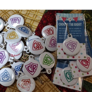 May include: White round pinback buttons with a shield design and the letters "CTR" in various colors, including purple, red, blue, green, and yellow. Some buttons have a metal clasp. A card with the text "CHOOSE THE RIGHT" is also visible.