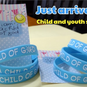 May include: A stack of blue silicone bracelets with the text "I am a child of God" and a smiley face sun. The bracelets are available in child and youth sizes.