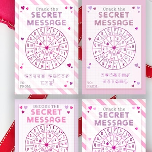 May include: Four pink and white Valentine's Day cards with a cipher wheel design and the text "Crack the Secret Message" or "Decode the Secret Message". A pink heart and ribbon are also visible.