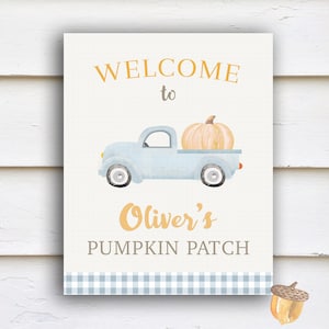 May include: A welcome sign for Oliver's Pumpkin Patch, featuring a blue truck with a pumpkin in the bed, a blue and white checkered border, and the text "Welcome to Oliver's Pumpkin Patch".