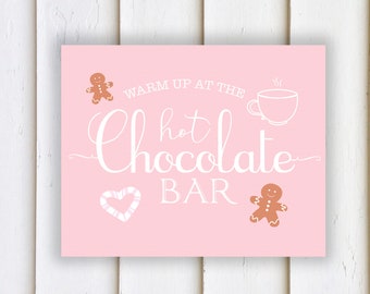 May include: Pink sign with white text that reads "Warm up at the hot chocolate bar". The sign features a gingerbread man, a cup of hot chocolate, and a candy cane heart.