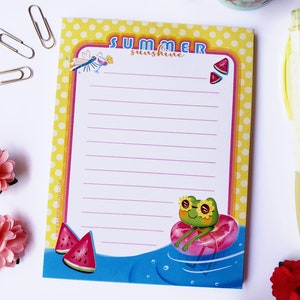 Puede incluir: Un bloc de notas amarillo y rosa con un tema de verano. El bloc de notas tiene un patrón de lunares y presenta una rana con gafas de sol y una rodaja de sandía. El texto "SUMMER sunshine" está impreso en el bloc de notas.