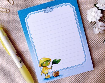 May include: A blue notepad with a white border and a cute cartoon illustration of a snail and a character wearing a yellow raincoat and holding a leaf. The notepad has lined paper and a cloud with a smiley face at the top.